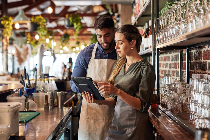 A barista teaches another barista how to utilize the tablet