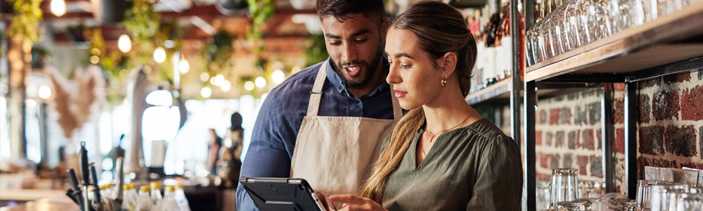 A barista teaches another barista how to utilize the tablet