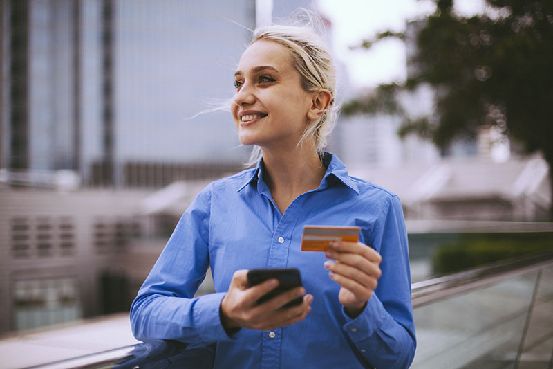 Young businesswoman holding credit card and using smart phone in the city, Hong Kong, China