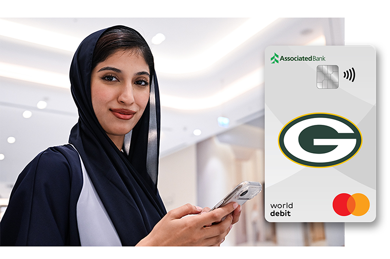 A woman looks at the camera while holding her phone. The Associated Bank Packers credit card is superimposed on the image.