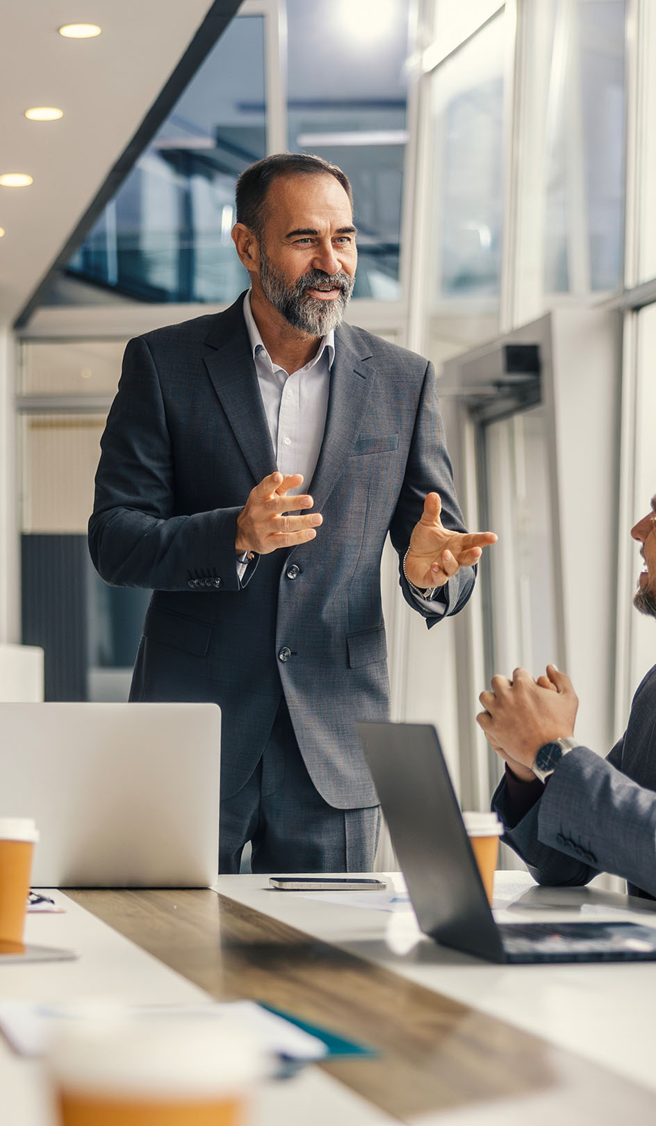 A businessman stands and pitches his idea to table of colleagues