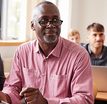 An older man sits in a classroom