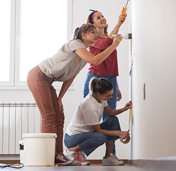 Three women paint a room together