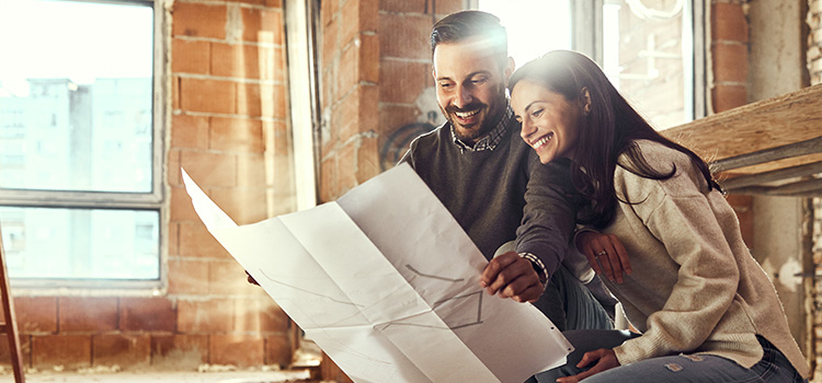 A happy couple looks at the blueprints for their home renovation