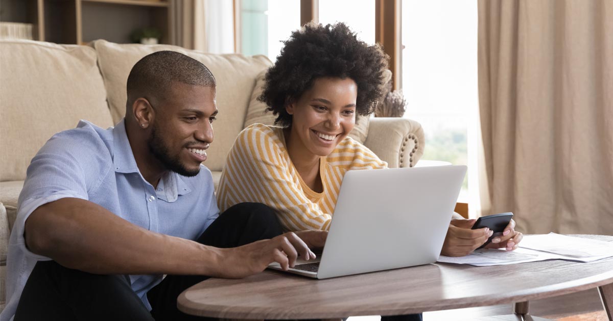 A couple look at their laptop and plan their finances for purchasing their next home