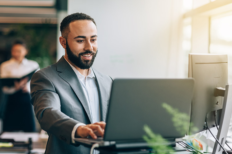 A businessman works on his laptop at his standing desk
