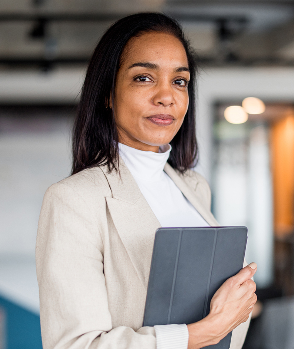 A business woman looks directly into the camera while holding her tablet