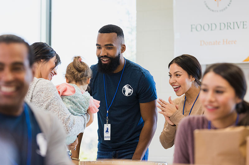 Food drive volunteer talking organizer to a woman and her baby