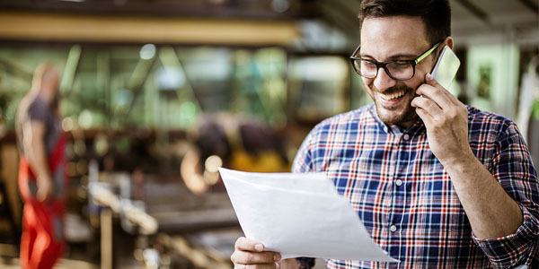 a man talks on the phone while looking at a document on a job site