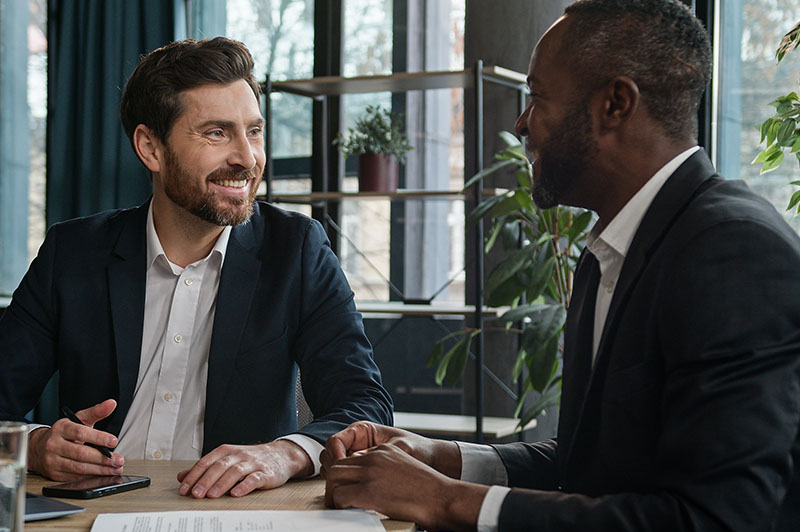 Two businessmen speak to one another