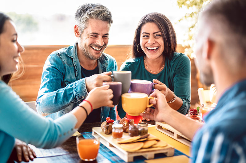 People group toasting latte at coffee bar rooftop - Friends talking and having fun together at cappuccino restaurant - Life style concept with happy men and women at cafe terrace - Bright warm filter