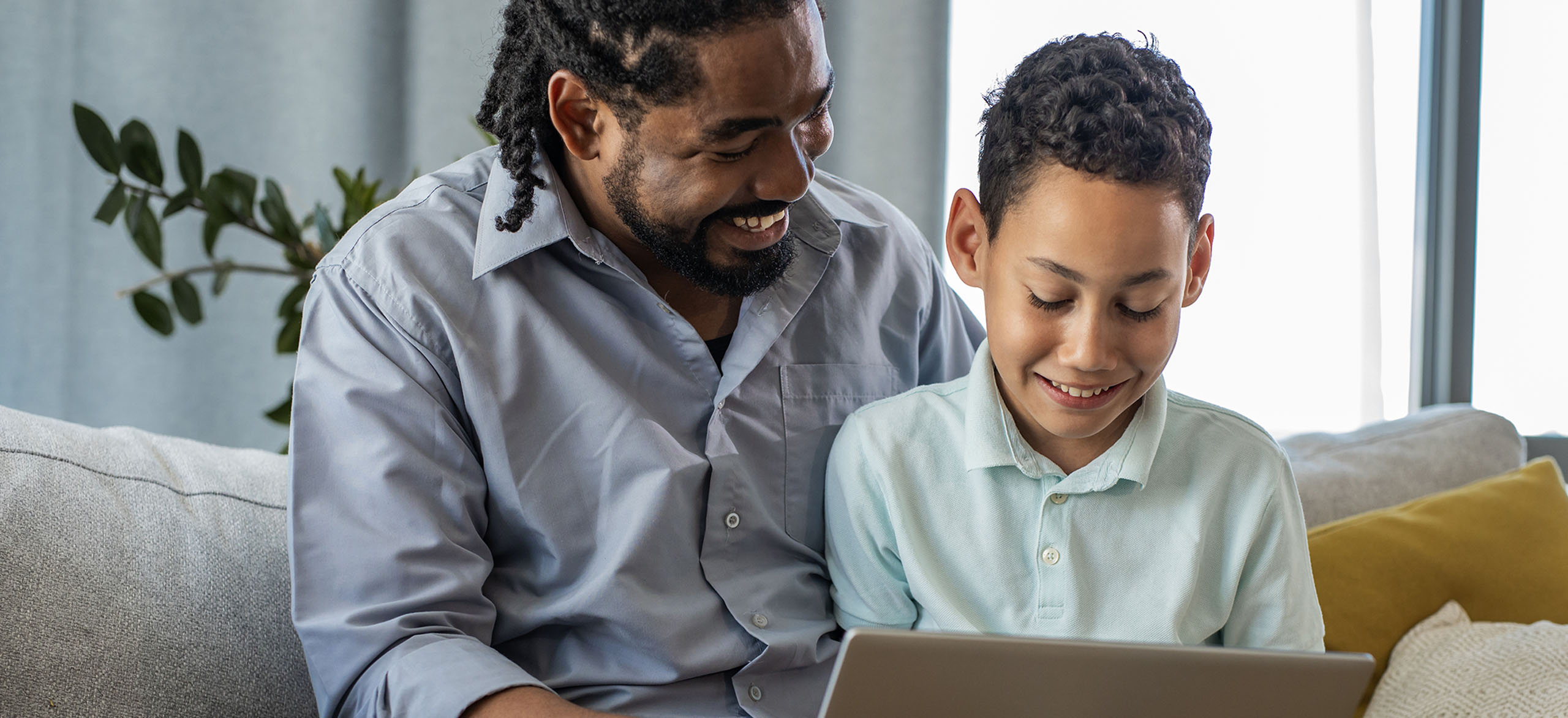 A father and son reviewing the son's bank account together online.