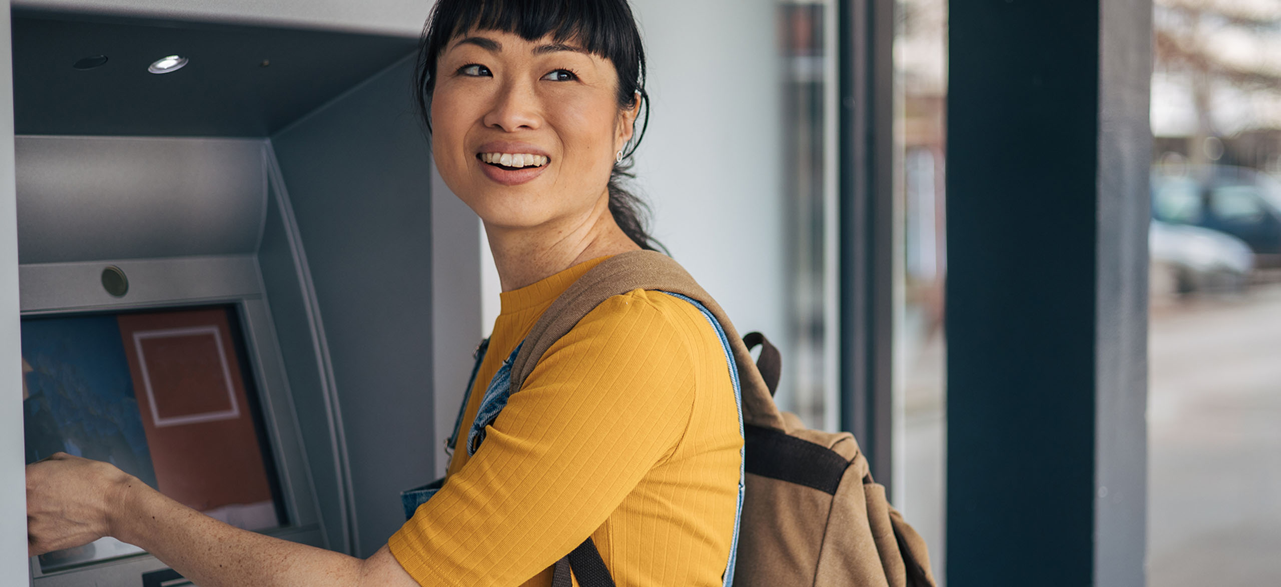 A teen using her debit card at an ATM kiosk.