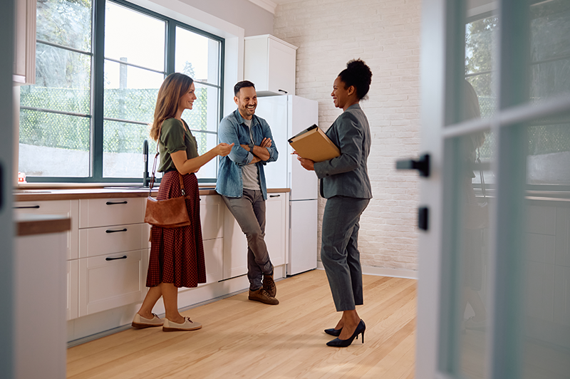A happy couple meets with their realtor at a house