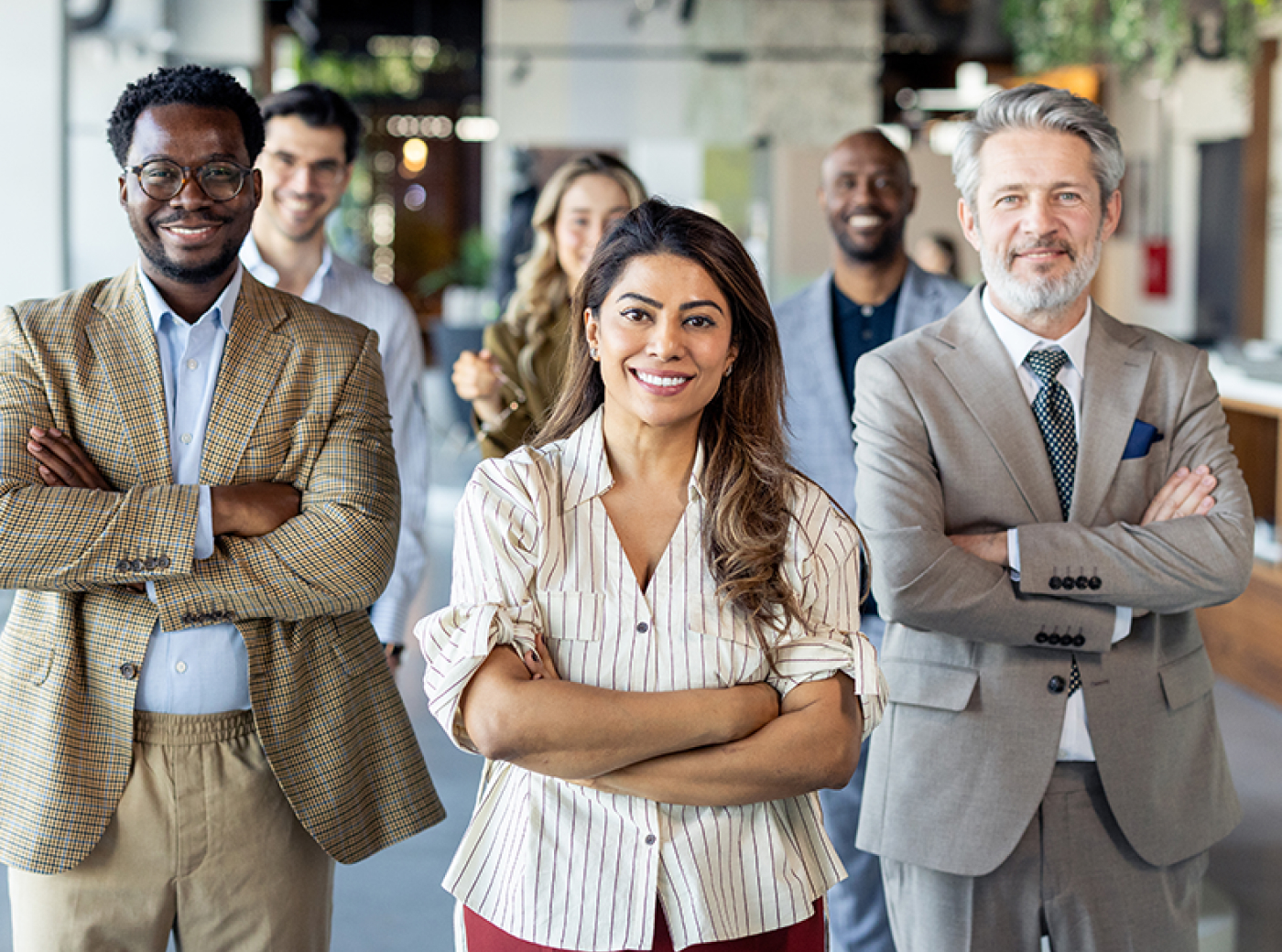 A group of six business people smile into the camera with their arms crossed