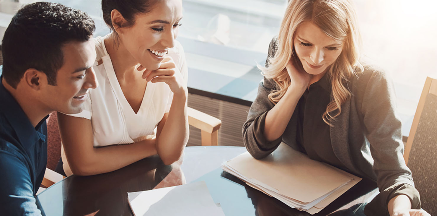 Three colleagues work together in front of window and the sun shines on them