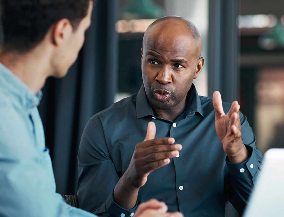 A man sternly explains something to a colleague with his hands