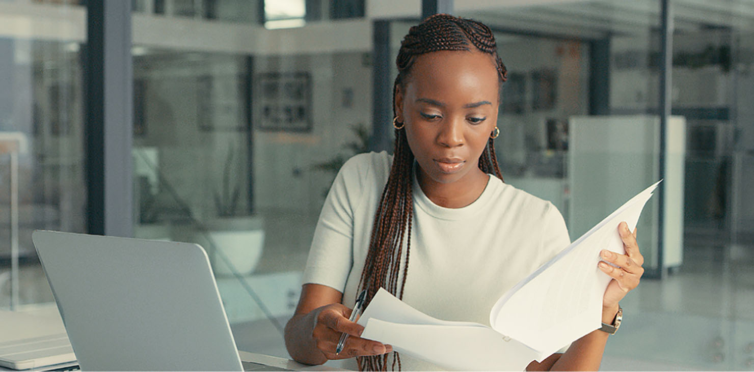 A woman pages through a packet of information at her desk