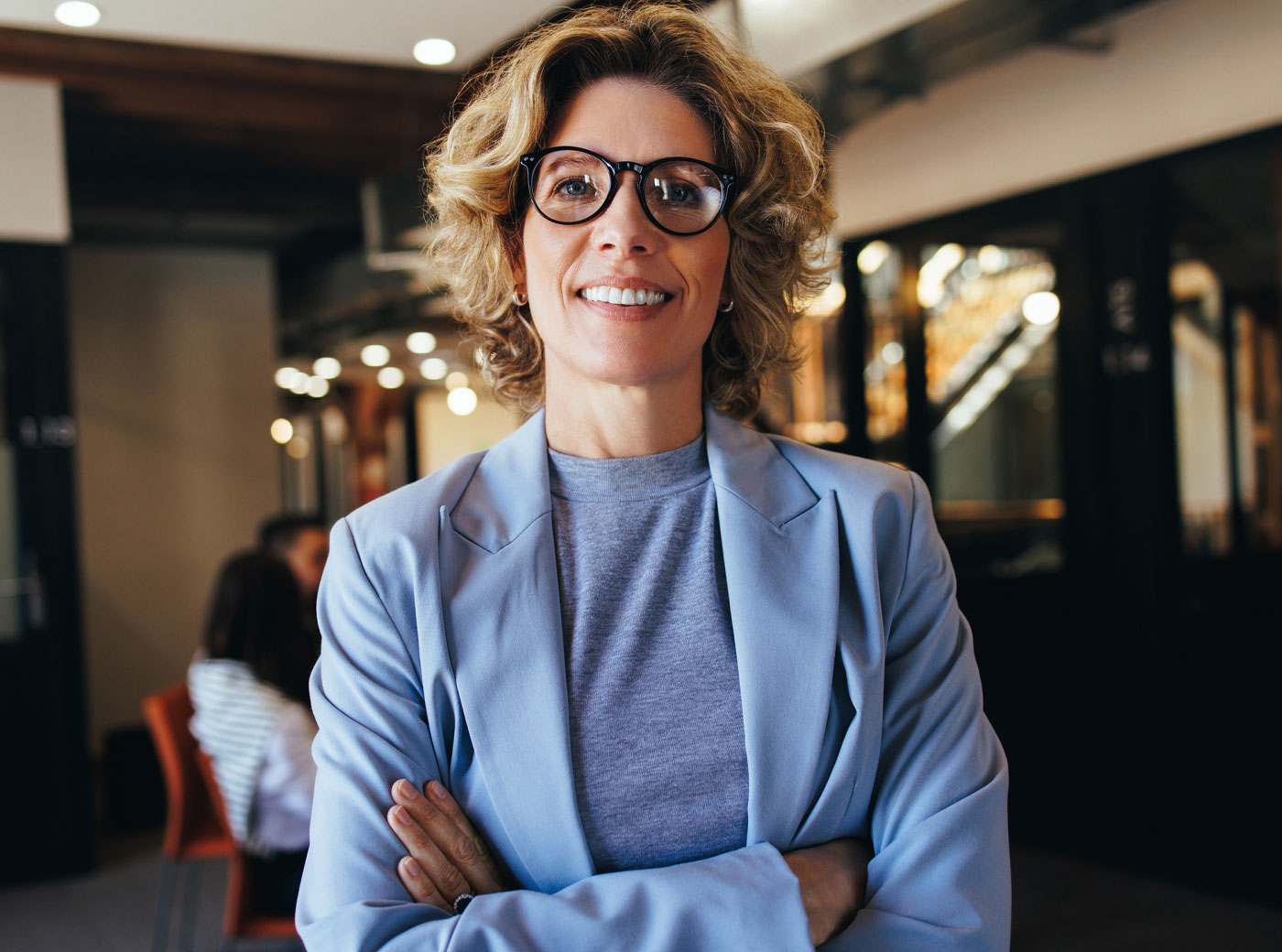 A woman with short hair types at her laptop and looks into the camera