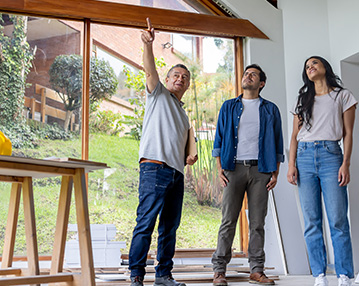 A builder shows a couple how their home improvement construction is going