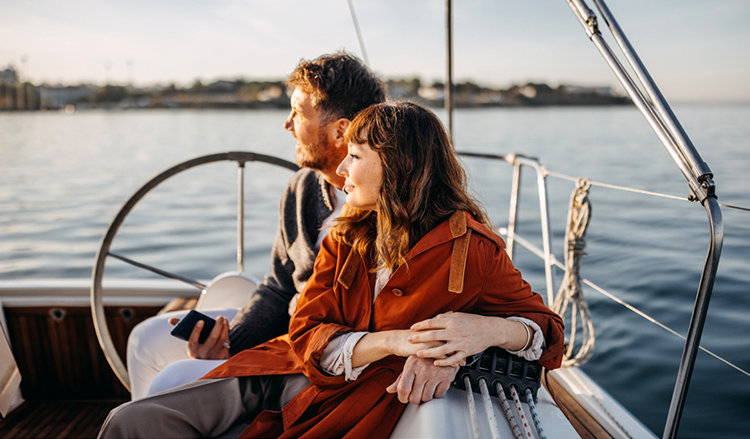 A couple look off into the distance while sitting in a boat on the water