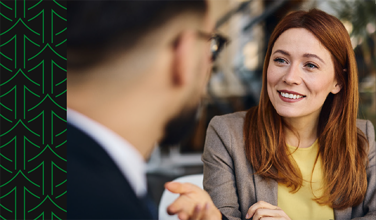 A red haired woman speaks to a man with glasses