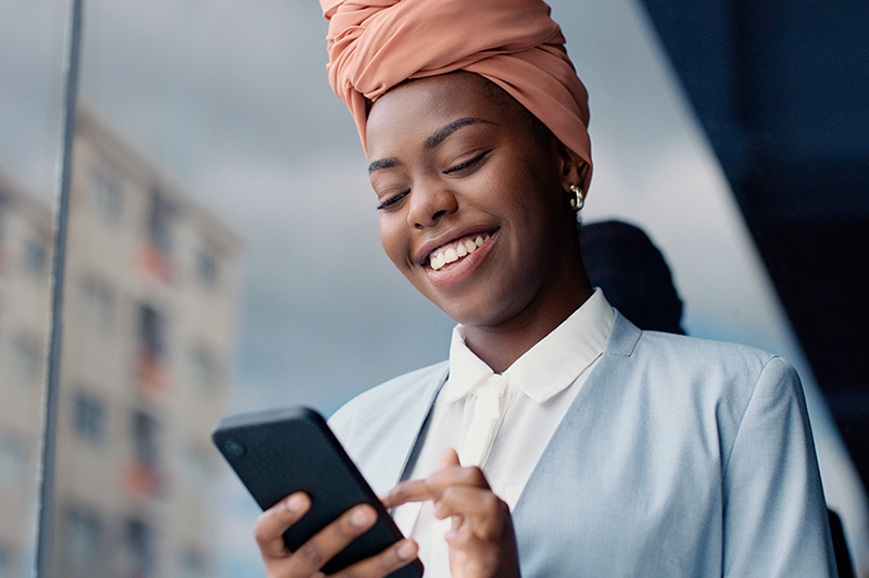 A business woman smiles while typing on her phone